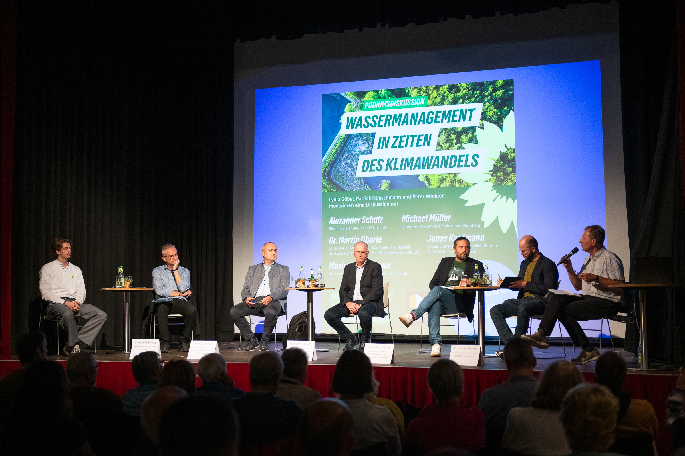 Teilnehmer und Moderatoren der Podiumsdiskussion auf der Bühne